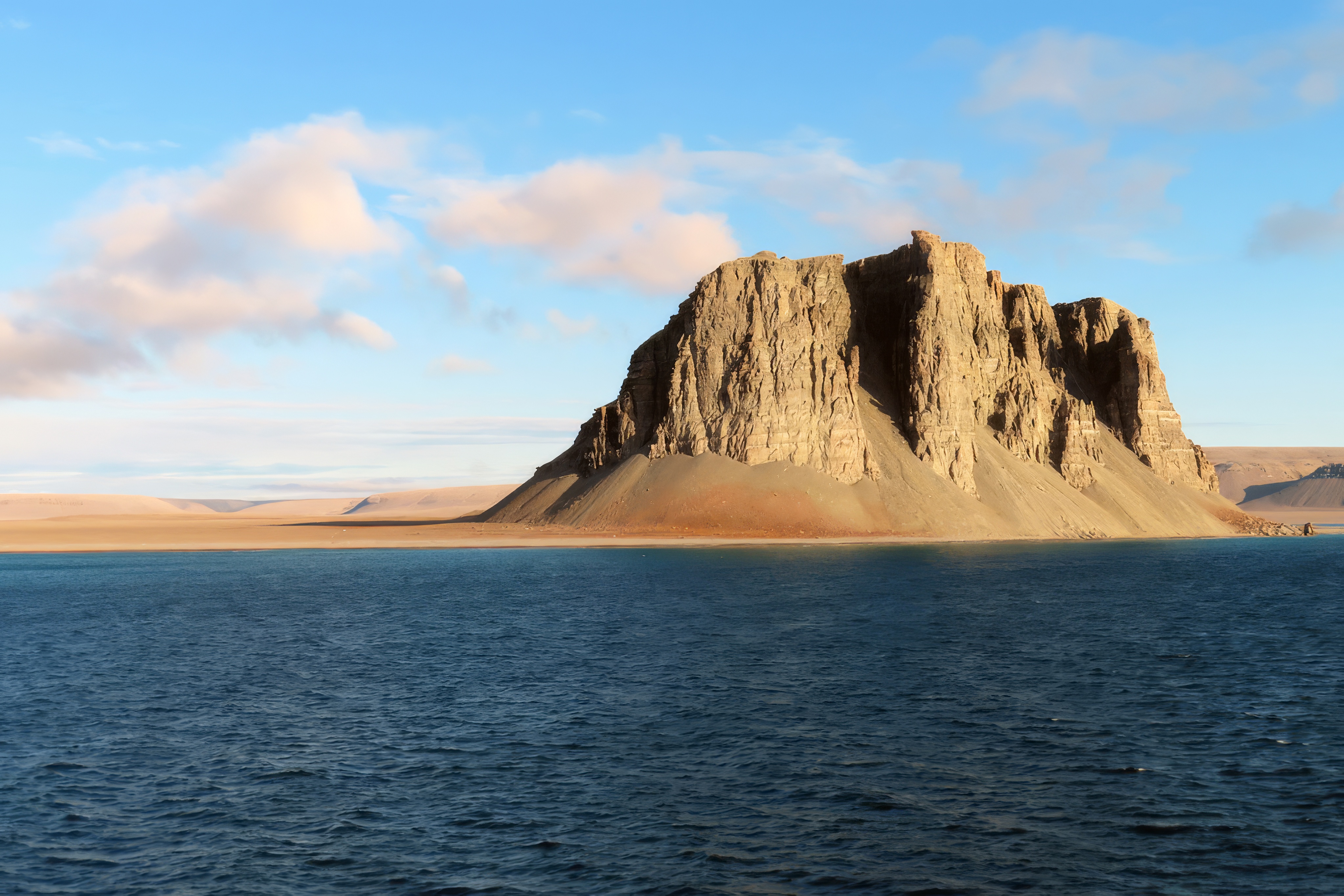 Photo of Caswell Tower, an isolated rock or bluff rising on the coast, on the west side of Radstock Bay on the southern coast of Devon Island in August 2023.